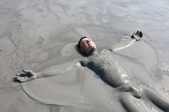 Man lying in mud pond
