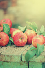 Red apples on the wooden table in sunlight close up
