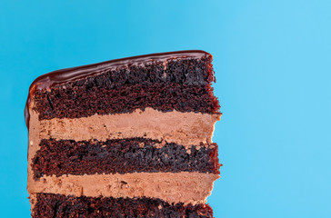 Chocolate layered cake slice. Close-up on blue background