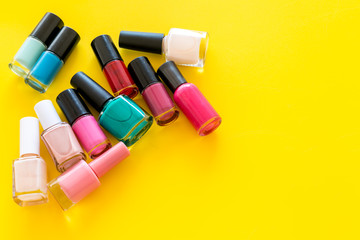 Choose nail polish. Polish bottels on yellow background top view copy space