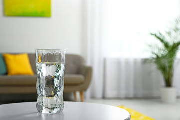 Glass of water on table in room, space for text. Refreshing drink