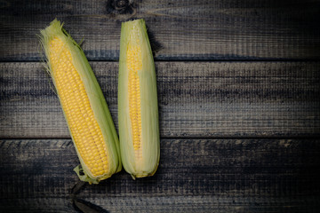 Corn on the dark wooden table. The concept of eating and eating meals. Preparation of corn dishes, boiled corn and popcorn.