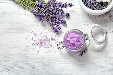 Flat lay composition with natural sugar scrub and lavender flowers on white wooden table, space for...