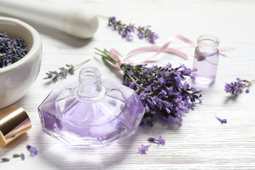 Obraz na płótnie Canvas Bottle of natural perfume and lavender flowers on white wooden table. Cosmetic product