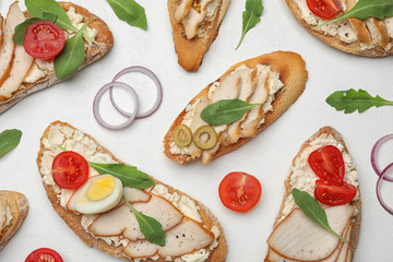 Different delicious chicken bruschettas on white table, flat lay