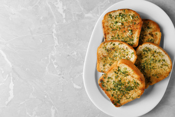 Slices of toasted bread with garlic and herbs on grey table, top view. Space for text