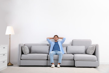 Young man relaxing on sofa at home - Powered by Adobe