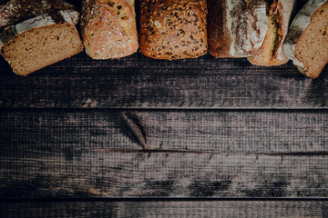 Top view of bread on a dark wooden background. The concept of baking bread, eating meals with rolls, bread. Product made of wheat and rye flour, bread preparation.