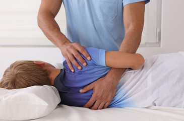 Bad posture correction. Osteopathy, Physiotherapy and Kinesiology taping for children. Boy having...