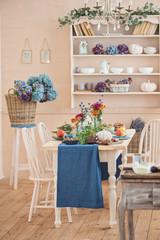 Living room with festive served atumn table, white wooden chair and basket with flowers
