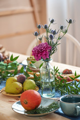 Flower in vase, pumpkin, pear, green and cup of tea on the served table