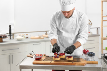 Male pastry chef preparing desserts at table in kitchen