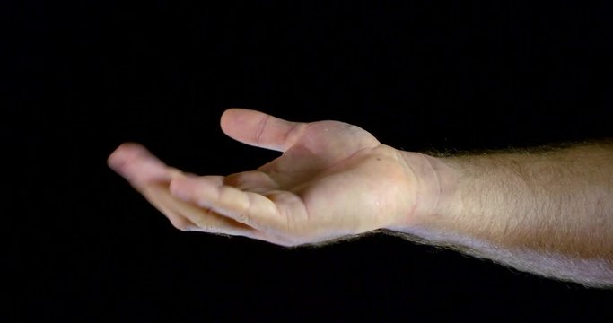 Close - up of a man's hand in a white sleeve on a black background in the Studio, she shows a finger sign "come here", then shows a sign "super".