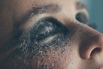 Fototapeta premium A stunning make-up on the face of a beautiful young girl, beauty makeup, oil on her face and sparkly green with priority red