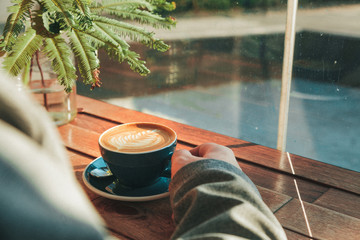 Man in coffee shop drinking latte art with plant