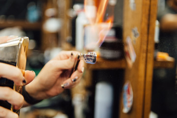 The hands of young barber making haircut to attractive man in barbershop