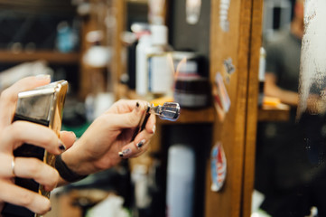 The hands of young barber making haircut to attractive man in barbershop
