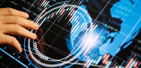 Businessman is pointing on a hi technology futuristic digital screen with financial analytics