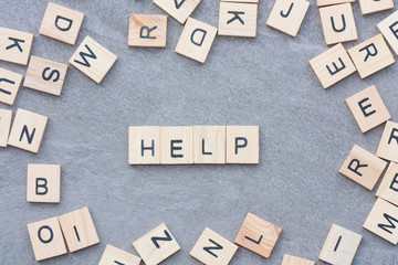 Wooden letters on grey background and word help.