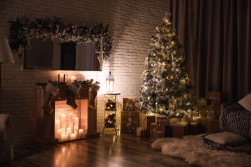 Stylish interior with beautiful Christmas tree and artificial fireplace at night