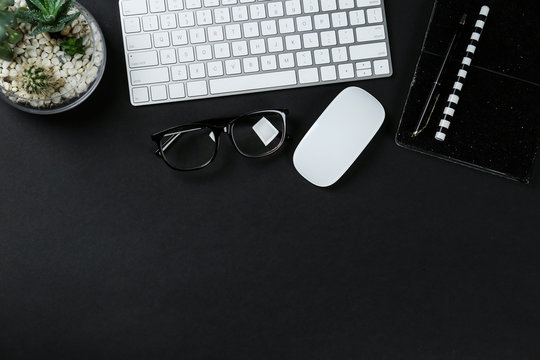 Flat lay composition with computer keyboard and notebook on black background, space for text. Graphic designer's workplace