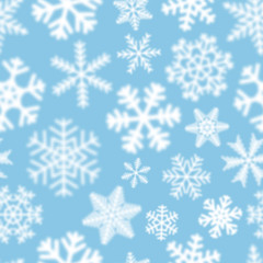 Fototapeta na wymiar Christmas seamless pattern of white defocused snowflakes on light blue background