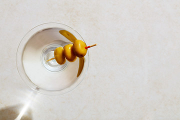 Glass of dry martini with olives under hard summer sunlight