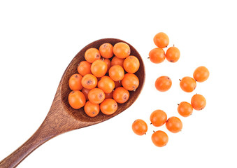 Fresh sea-buckthorn berries in wooden spoon isolated on white background, top view.