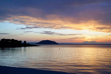 Obraz premium Horizontal shot. Empty beach in the evening at sunset. . Silhouettes and coastline. Sea bright sky. Greece Sithonia. Horizon. Clouds and rays of the sun. Bird island