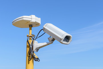 white CCTV camera on a blue sky background