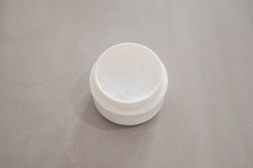 A beauty cream on a plastic container on a gray background