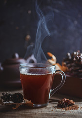 Hot black tea with steam on a wooden background, rustic style, autumn postcard, copy space