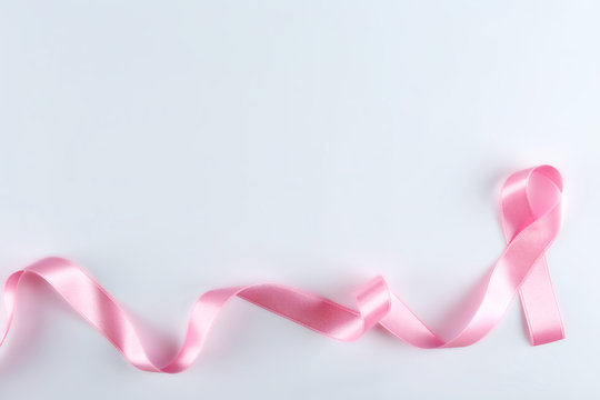 The pink colored ribbon - international symbol of breast cancer awareness and moral support for women. Isolated background, copy space, close up, top view fat lay.