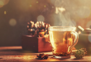 Black tea in glass cup on wooden table on the background of box with cone