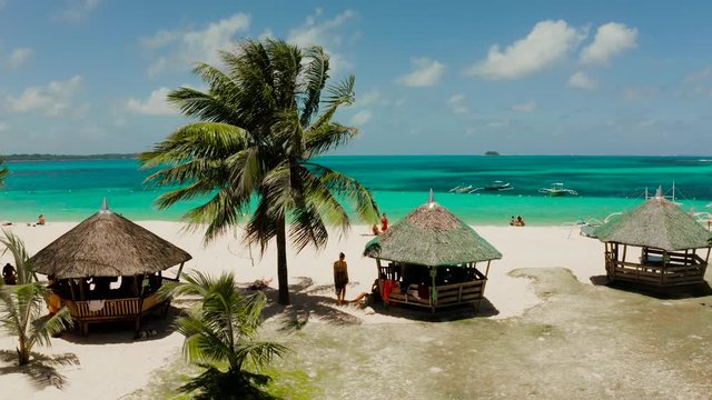 Daco island, Philippines. Palm trees and bungalows on the white sandy beach. People relax on a tropical island,view from above.