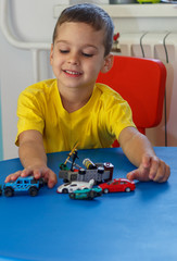 Little boy in yellow t-shirt playing with cars and toys at home, indoor