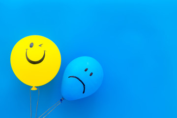 Treat depression concept. Balloons with sad and smiling faces on blue background top view copy space