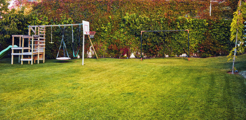Backyard garden of a house with children playhouse, basketball hoop and soccer goal post