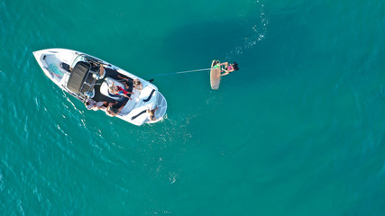 Aerial photo of woman practising waterski in Mediterranean bay with emerald sea at sunset