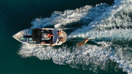 Aerial photo of woman practising waterski in Mediterranean bay with emerald sea at sunset