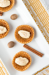 Sugar butter tart from above. Mini sugar pies (or butter tarts) with a crisp pastry crust, a sweet filling and pumpkin spice whipped cream on top. A tasty dessert for fall holidays like halloween!