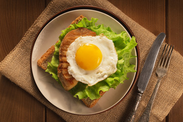 Fried egg and chicken on bread for breakfast on plate and rustic table