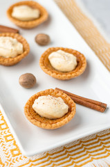 Sweet butter tartlet close-up. Mini sugar pies (or butter tarts) with a crisp pastry crust, a sweet filling and pumpkin spice whipped cream on top. A tasty dessert for fall holidays like halloween!