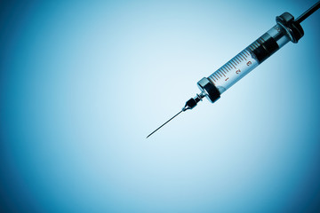 Vintage glass syringe on blue background