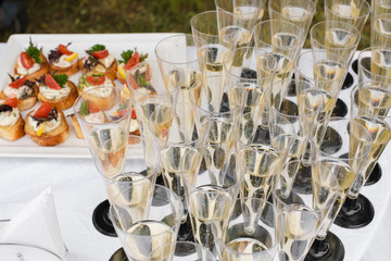 Close-up of many flutes of champagne or other fizzy drink with toasts with vegetables and cream cheese at wedding reception or banquet. Festive reception.