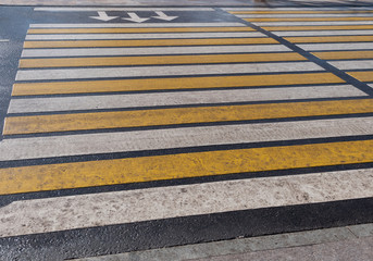Bright yellow and white stripes of zebra crossing, pedestrian crosswalk.