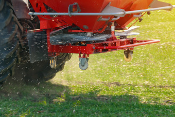 Agricultural tractor fertilizing wheat crop field with NPK