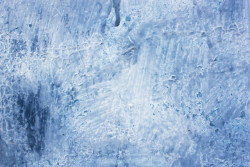 Shabby old fence covered faded blue paint with white smudges on stucco, abstract grunge texture of peeling light paint on worn wall.