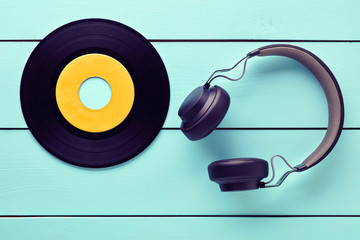 Vinyl record and a headphone on blue wooden table background