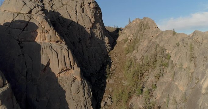 Aerial: Drone moving over rocky mountains with trees against sky during sunny day - Ulaanbaatar, Mongolia